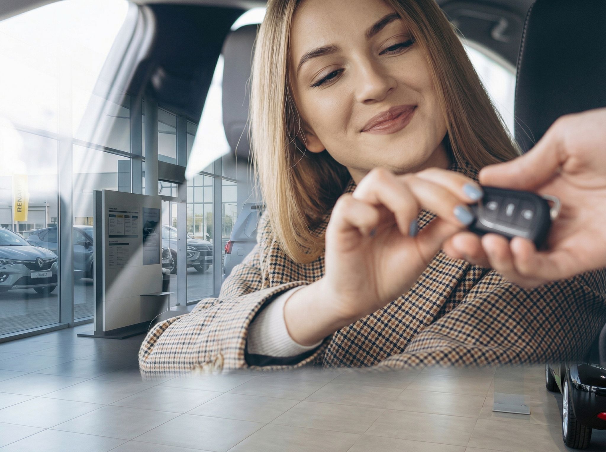 Frau mit Autoschlüssel im Fahrzeuginnenraum - Fahrzeugübergabe im Autohaus