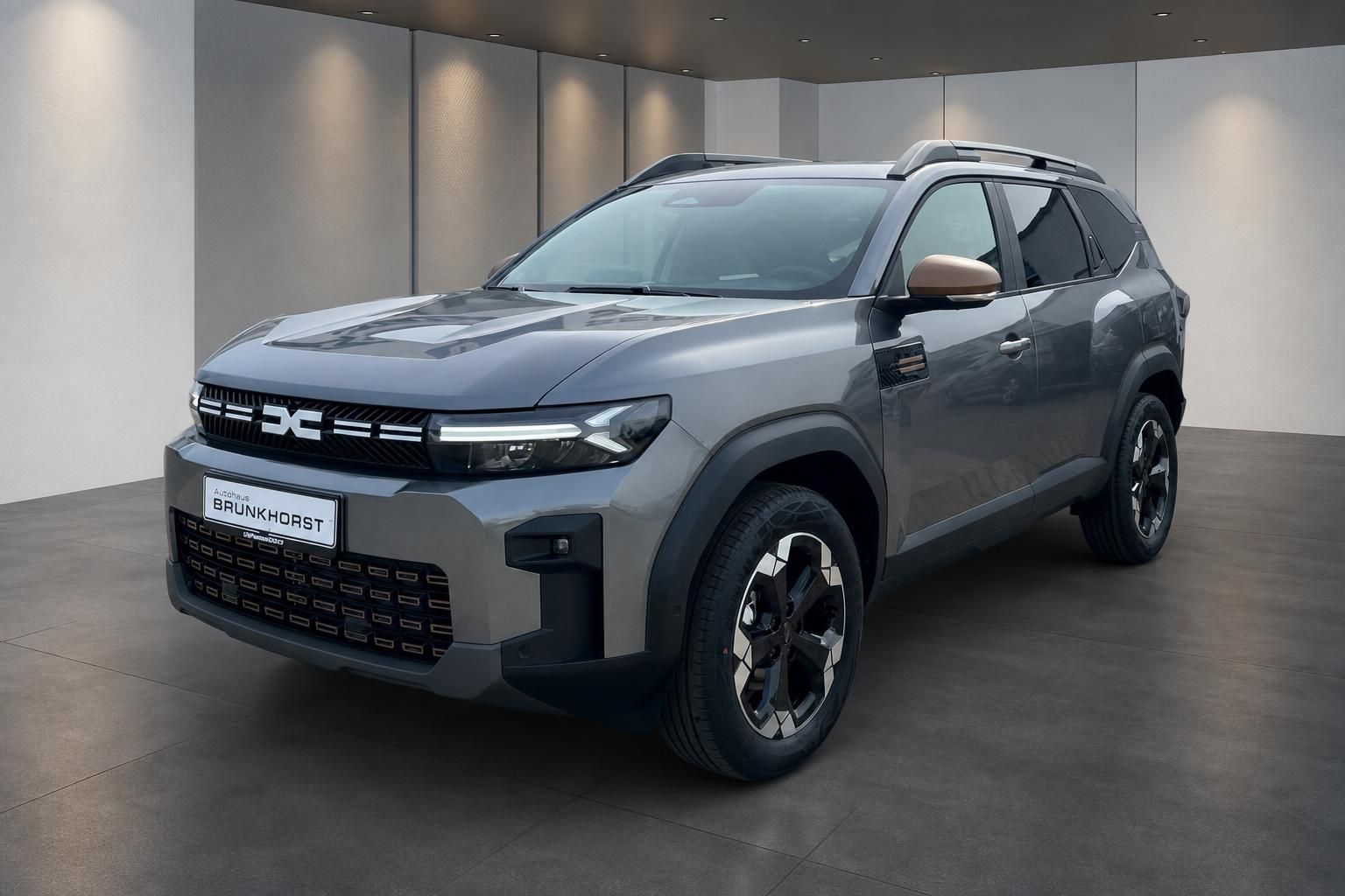 Grauer Dacia SUV von schräg vorne im modernen Showroom - Brunhorst Autohaus