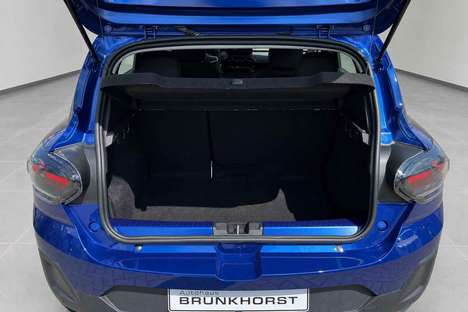 Blaues Fahrzeug mit geoeffneter Heckklappe und leerem Kofferraum