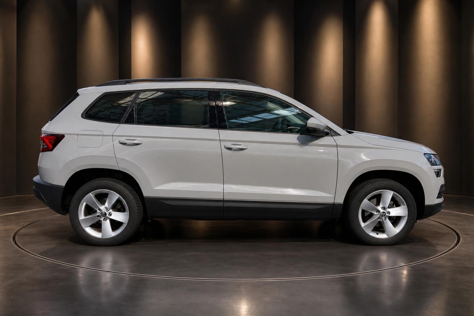 Weißer Skoda Karoq SUV Seitenansicht mit Alufelgen in modernem Showroom
