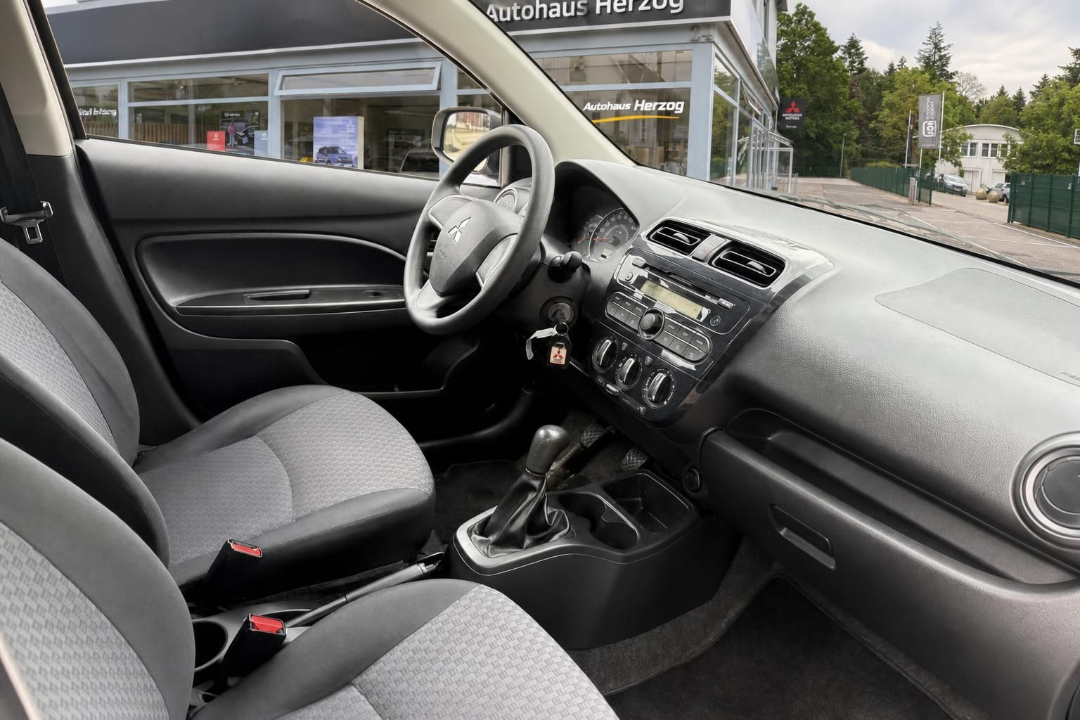 Mitsubishi Innenraum mit grauem Armaturenbrett und Mittelkonsole vor Autohaus Herzog