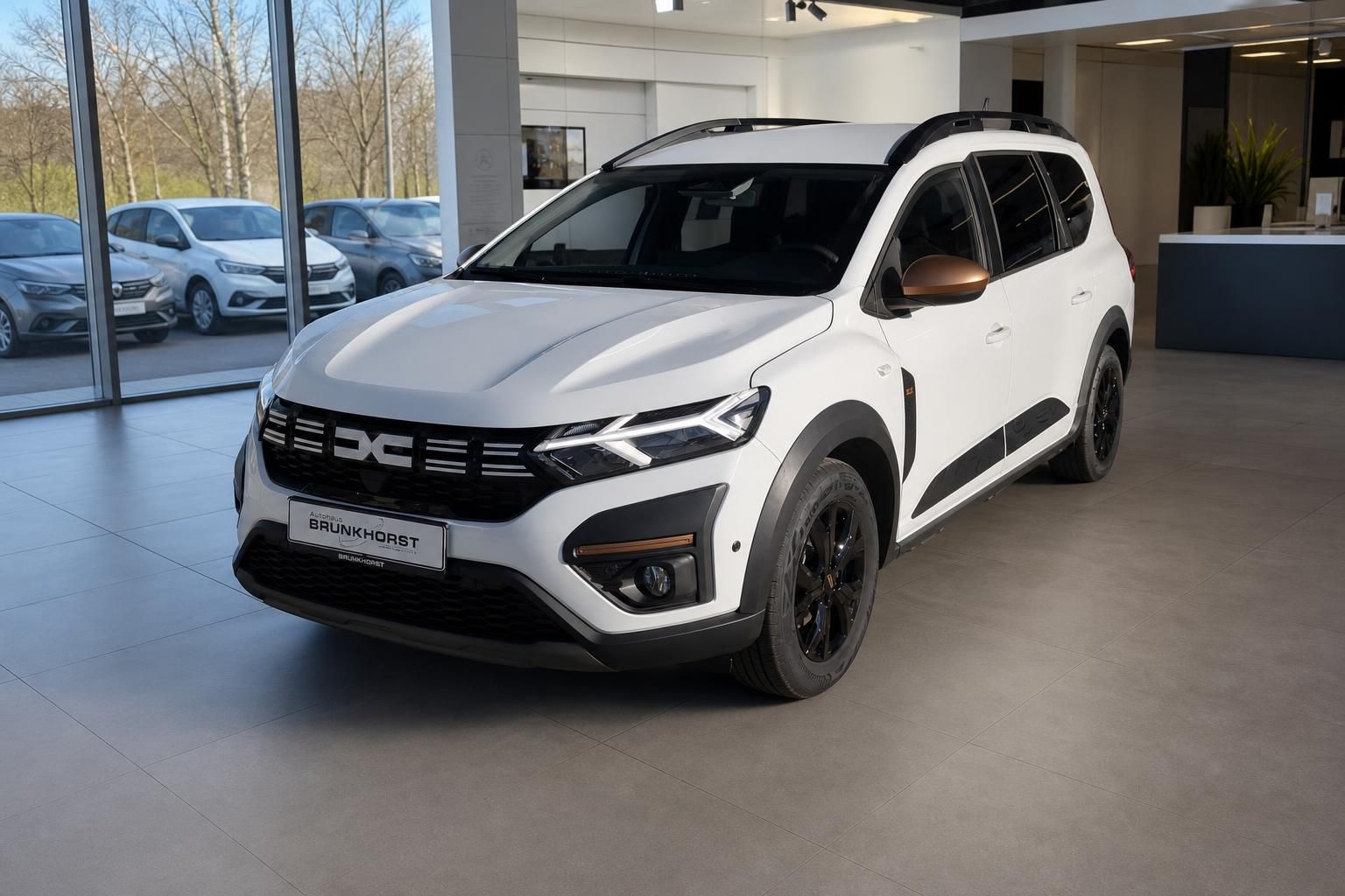 Weißer Dacia SUV Seitenansicht im Autohaus - sportliches Design mit schwarzen Felgen und Dachreleling