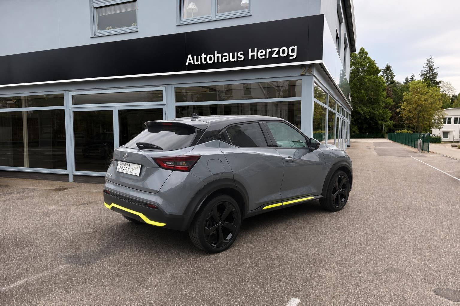 Nissan Juke SUV grau mit gelben Akzenten vor Autohaus Herzog Showroom