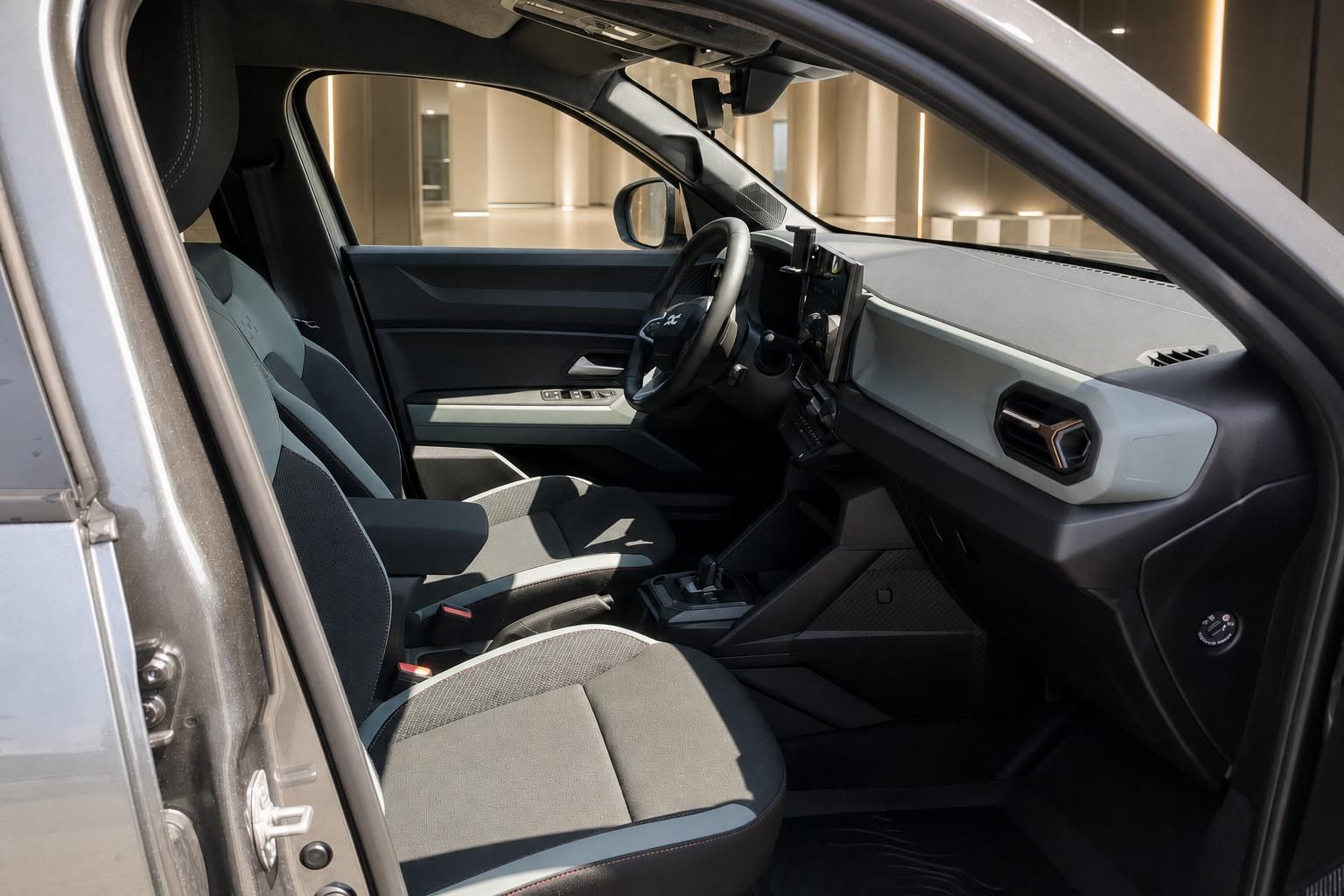 Blick durch geöffnete Fahrertür auf Sitze und Armaturenbrett des Dacia
