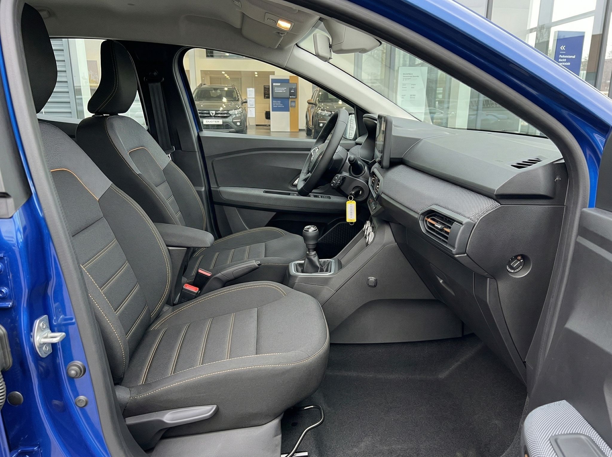 Dacia Fahrzeug Innenraum Beifahrerseite mit schwarzen Sportsitzen und blauer Karosserie