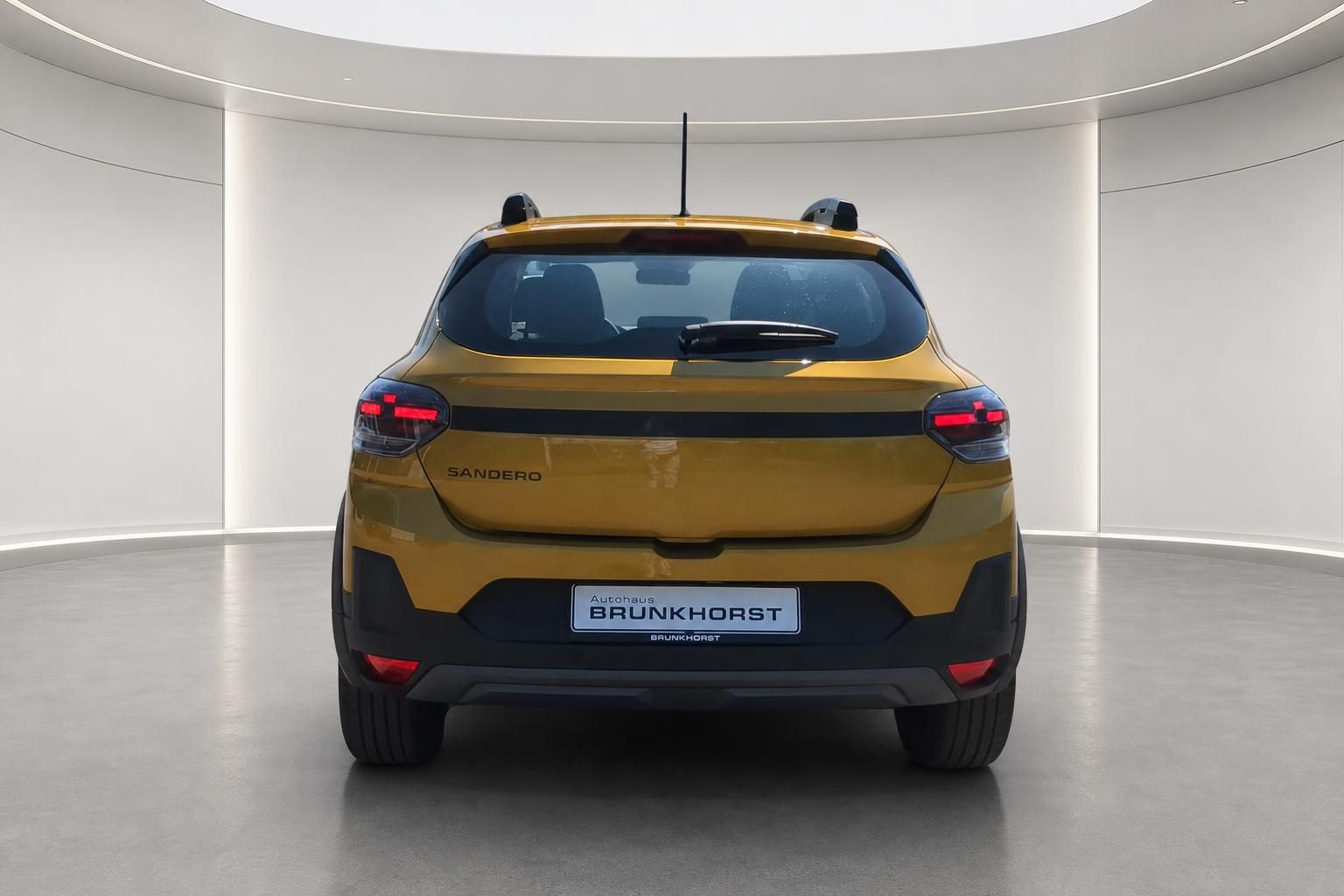Dacia Sandero gelb, Heckansicht in modernem Showroom