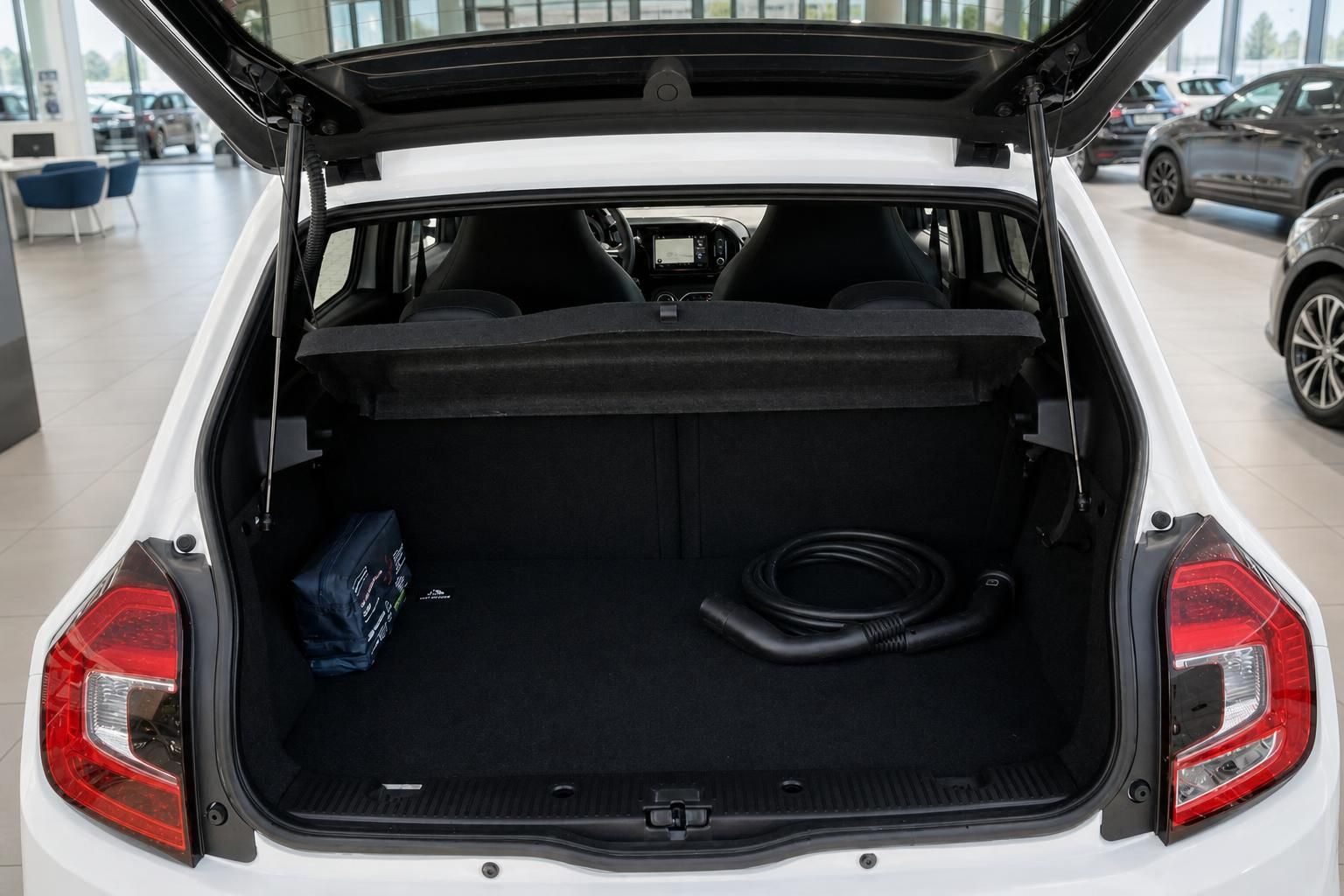 Geöffneter Kofferraum mit Ladekabel und Bordtasche – weißes Elektrofahrzeug im Autohaus