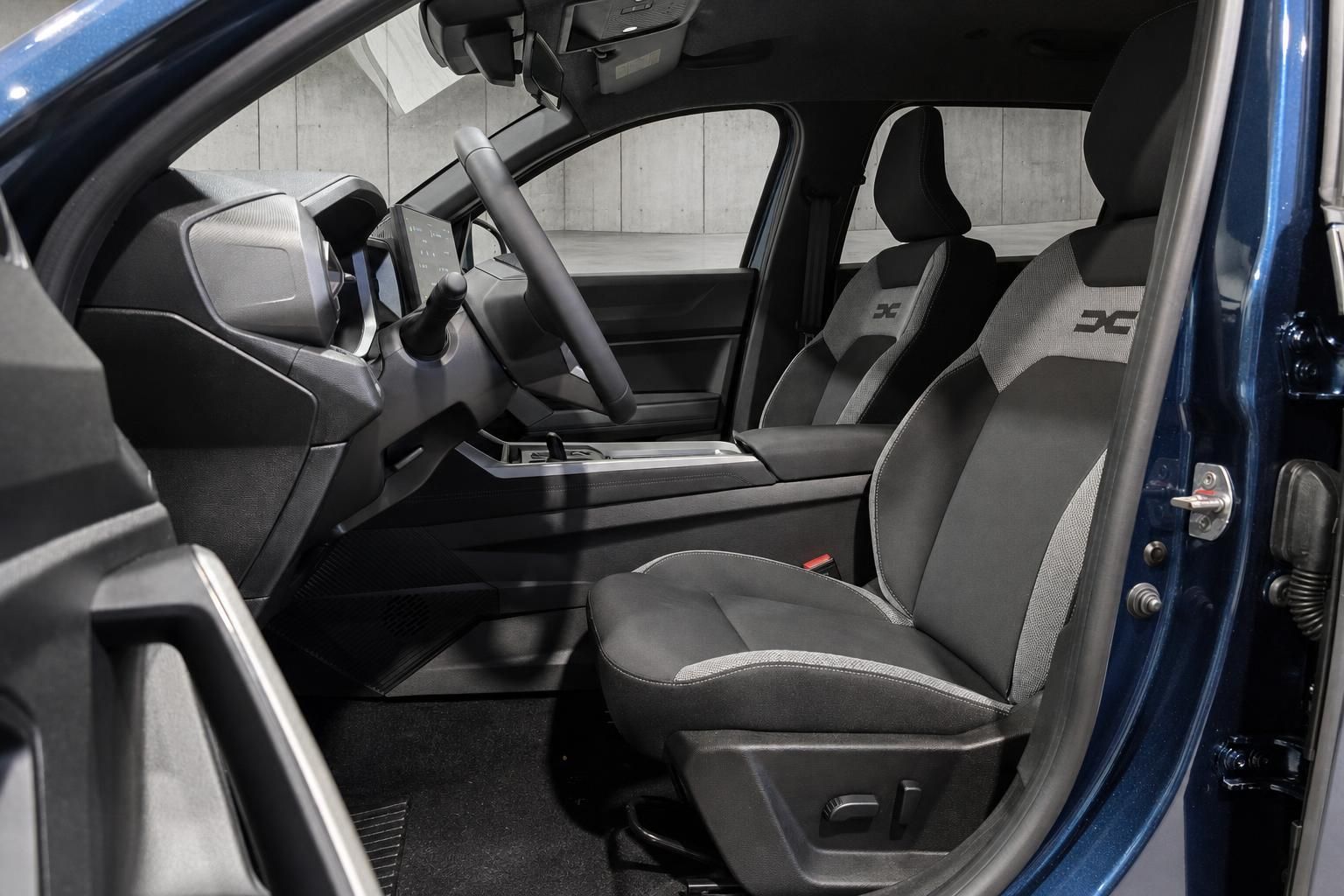 Blick durch geoeffnete Fahrertuer auf Vordersitze und Cockpit
