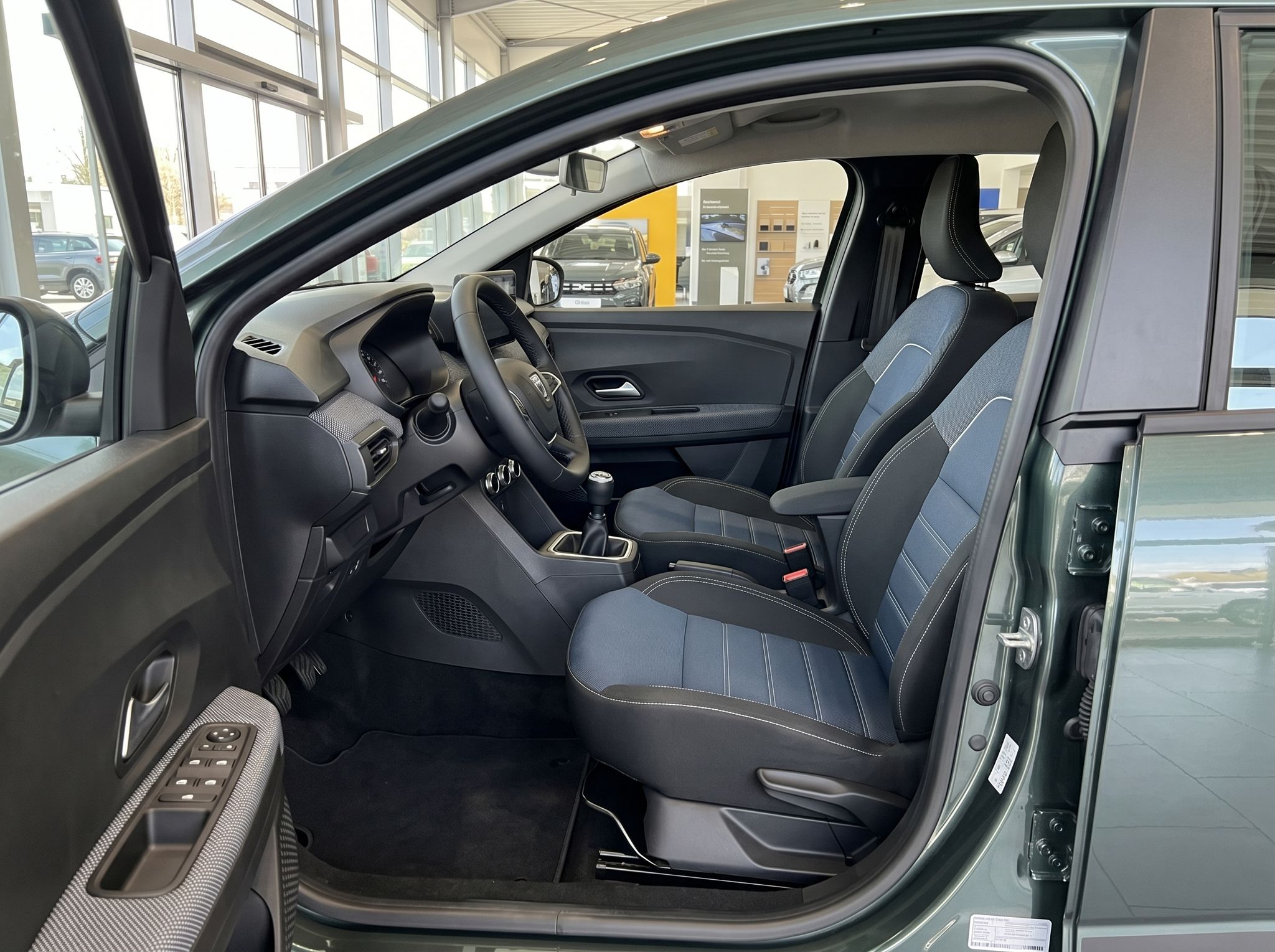 Dacia Innenraum Fahrersitz mit blau-schwarzer Polsterung und manuellem Getriebe