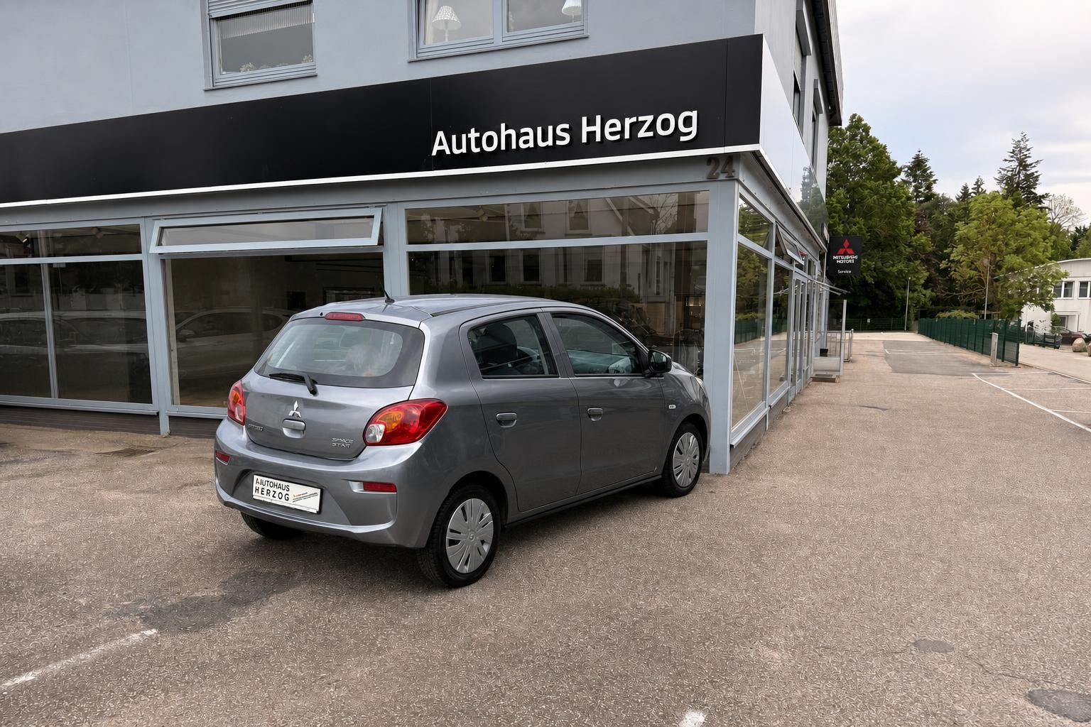 Grauer Mitsubishi Kleinwagen Heckansicht vor dem Autohaus Herzog Showroom