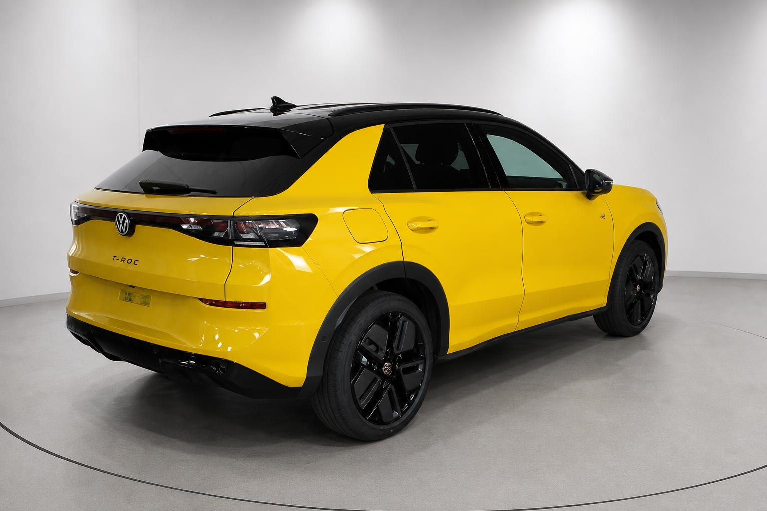 VW T-Roc gelb mit schwarzem Dach, Heckansicht im Showroom