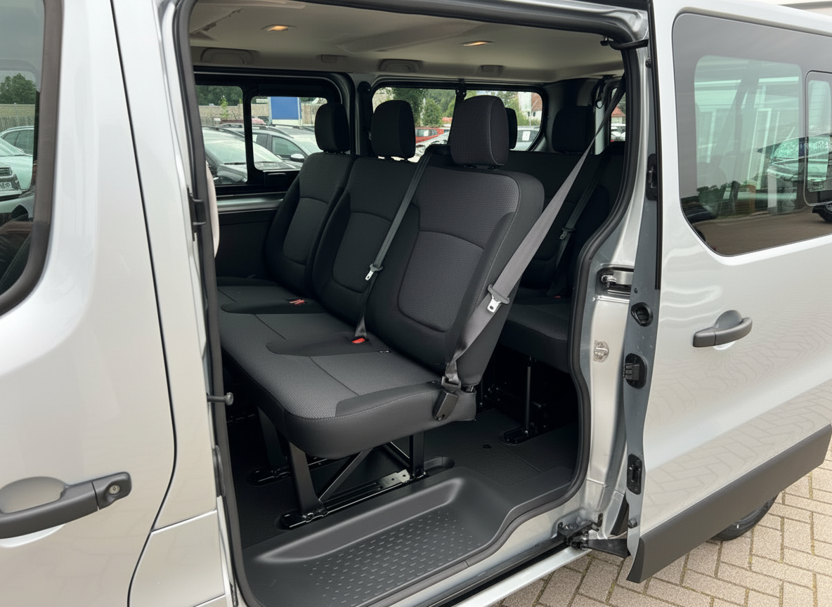 Silberner Van Innenraum mit schwarzen Dreisitzer-Rücksitzen und Sicherheitsgurten, Schiebetür offen