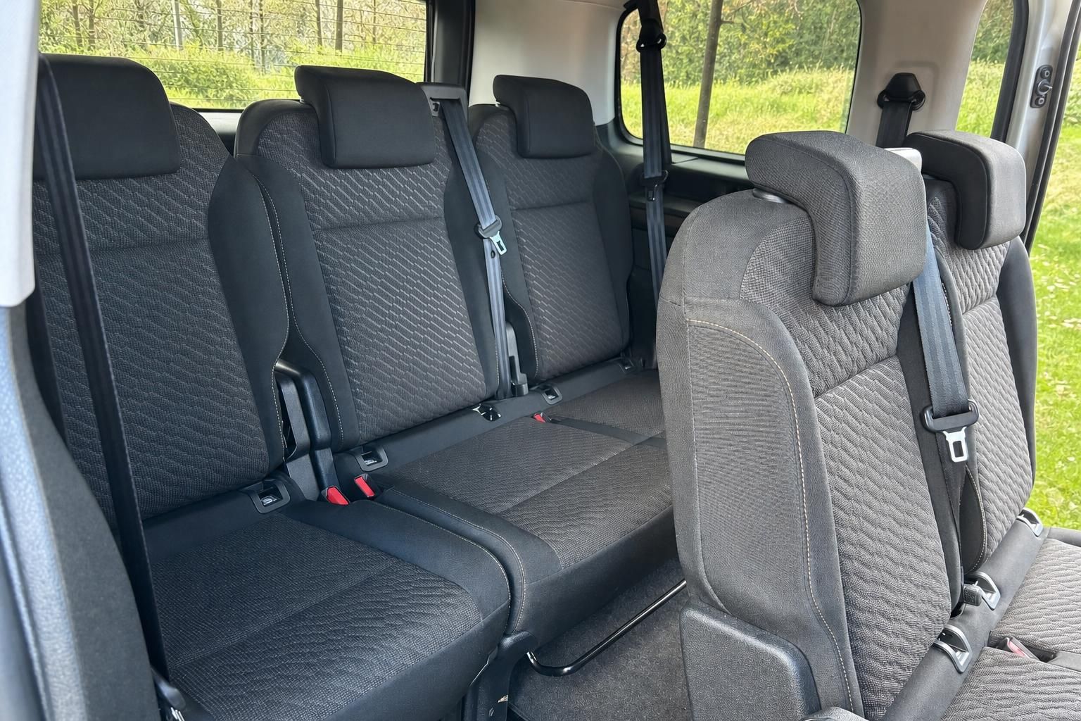 Toyota Van Innenraum - Rücksitzbereich mit Sicherheitsgurten und Fensterausblick in die Natur
