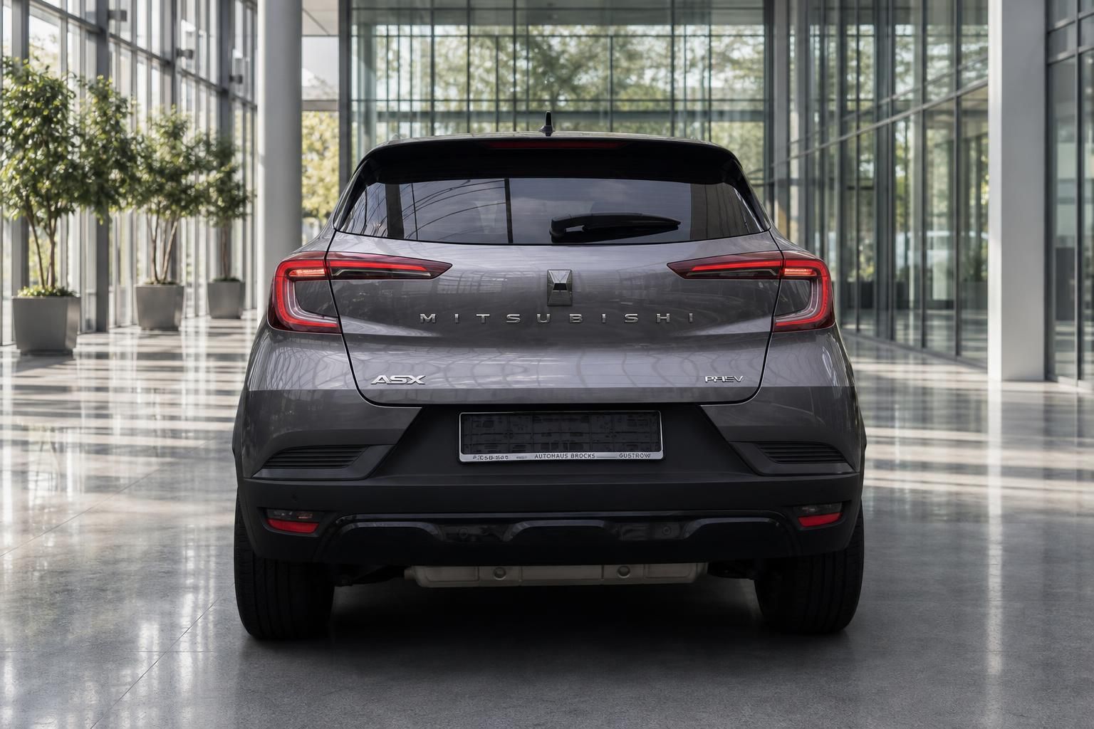 Mitsubishi ASX PHEV in Grau, Heckansicht in moderner Ausstellungshalle