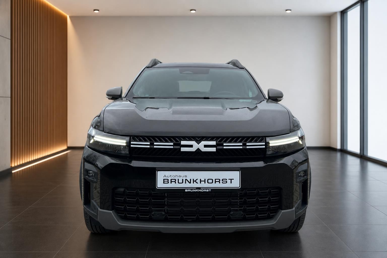 Dacia Bigster SUV in grau - Außenansicht Frontansicht mit charakteristischem X-Logo im Showroom