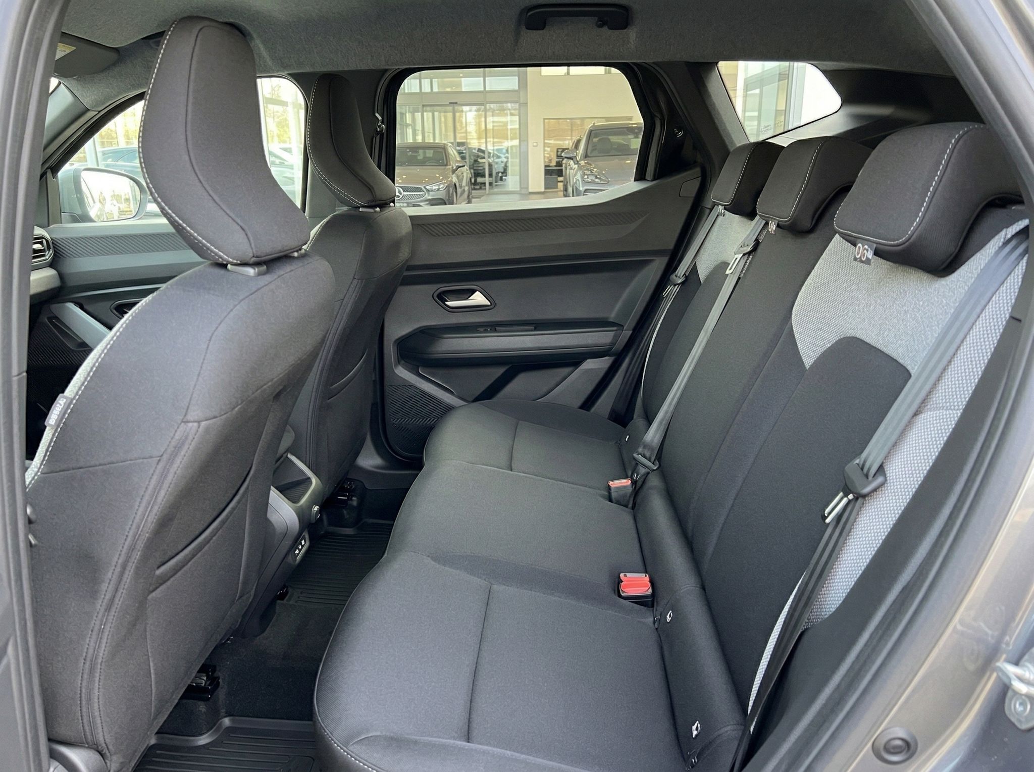 Rückbank eines Fahrzeugs mit grauen Stoffsitzen und Sicherheitsgurten für drei Personen