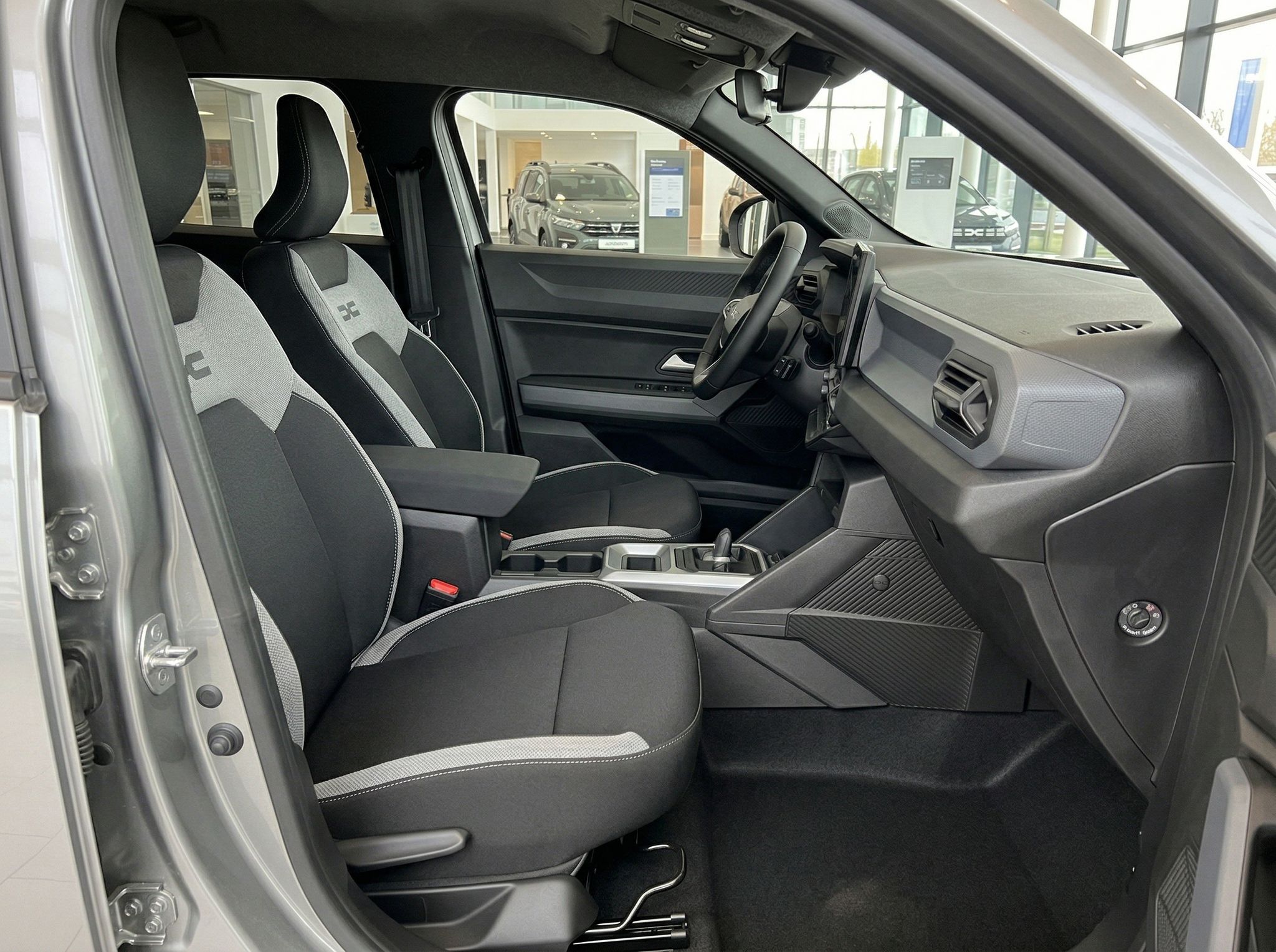 Fahrzeuginnenraum mit grauen Sportsitzen, Mittelkonsole und Blick auf die Fahrer- und Beifahrerseite