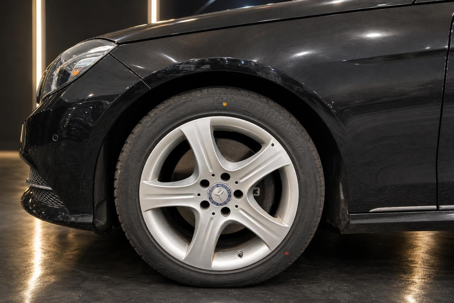 Mercedes Rad mit 5-Speichen-Felge und Mercedes-Stern auf schwarzem Fahrzeug