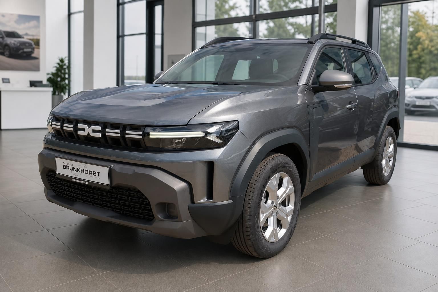 Grauer Dacia SUV in modernem Autohaus-Showroom - Dreiviertel-Ansicht von vorne