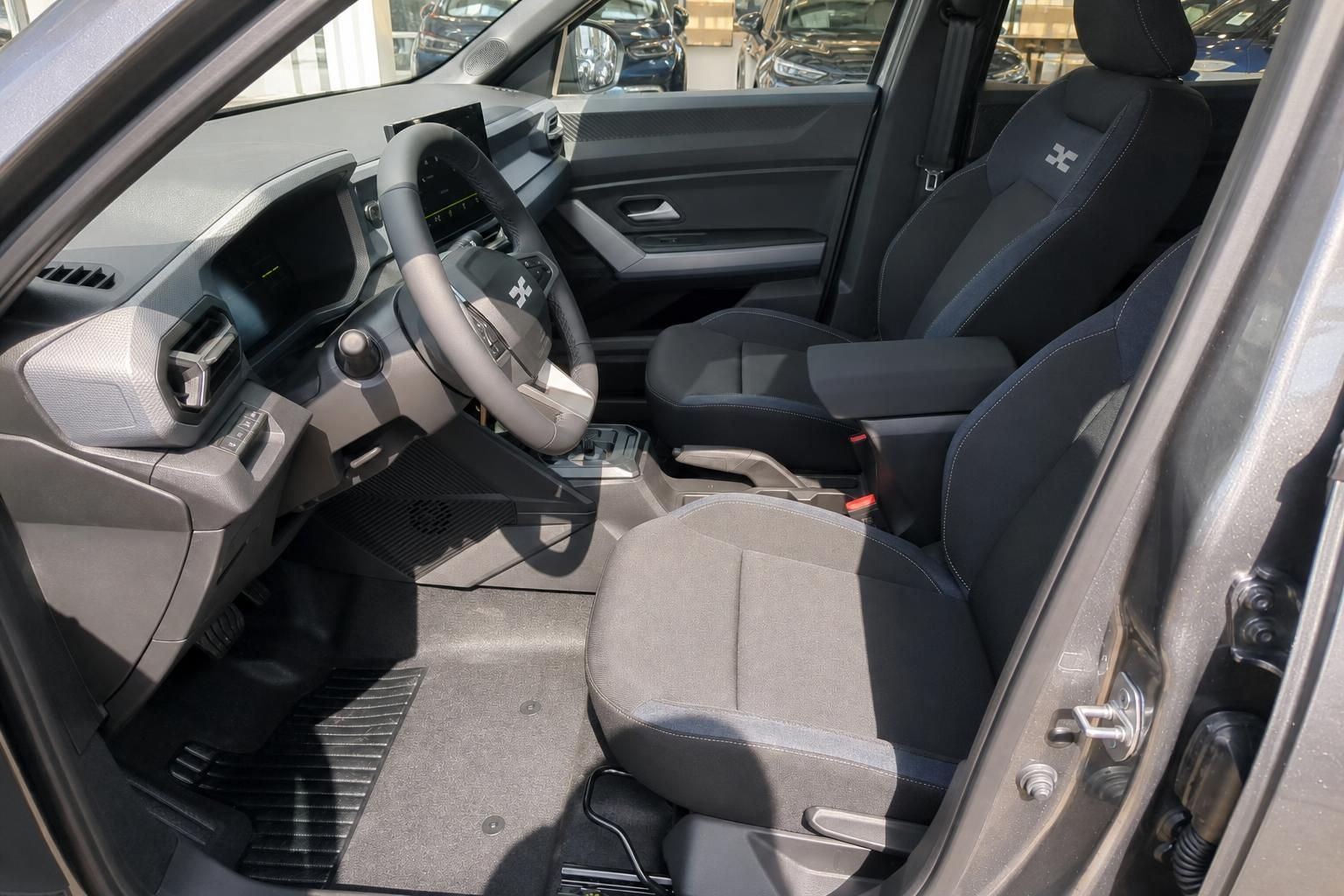 Dacia Innenraum mit Fahrersitz, Lenkrad und modernem Armaturenbrett in Grau-Blau