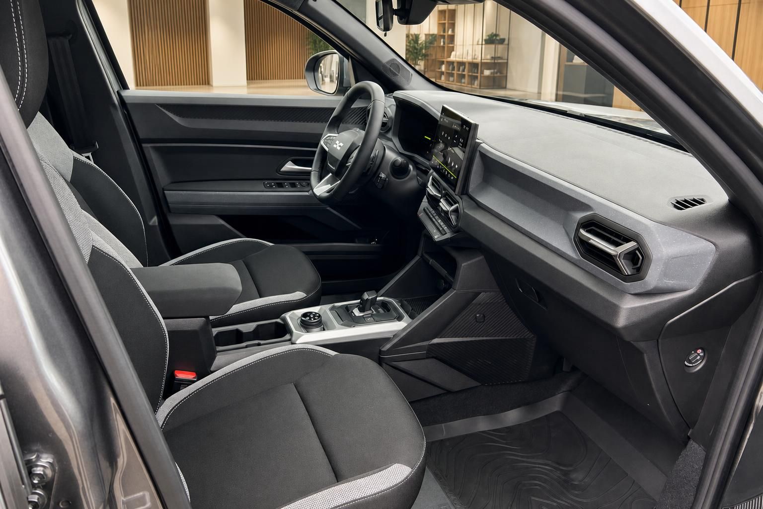 Dacia Innenraum Beifahrerseite mit schwarzen Stoffsitzen, Mittelkonsole und Armaturenbrett