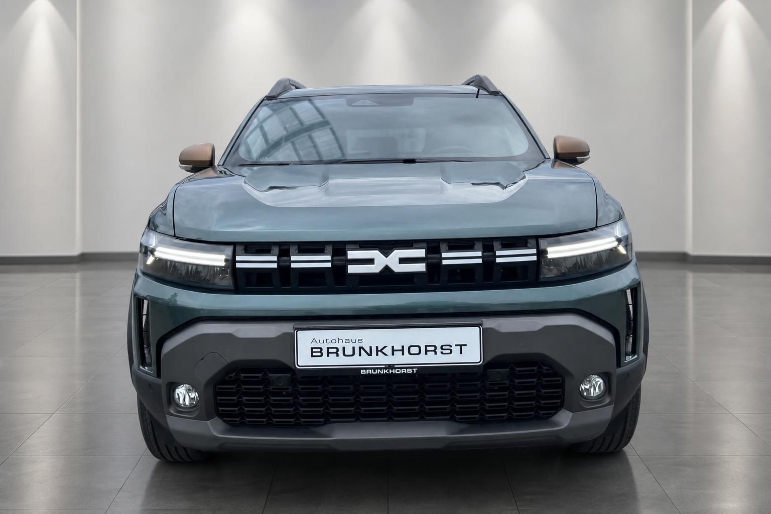 Dacia Duster Frontansicht in graugrün mit DC-Logo im modernen Autohaus Brunkhorst