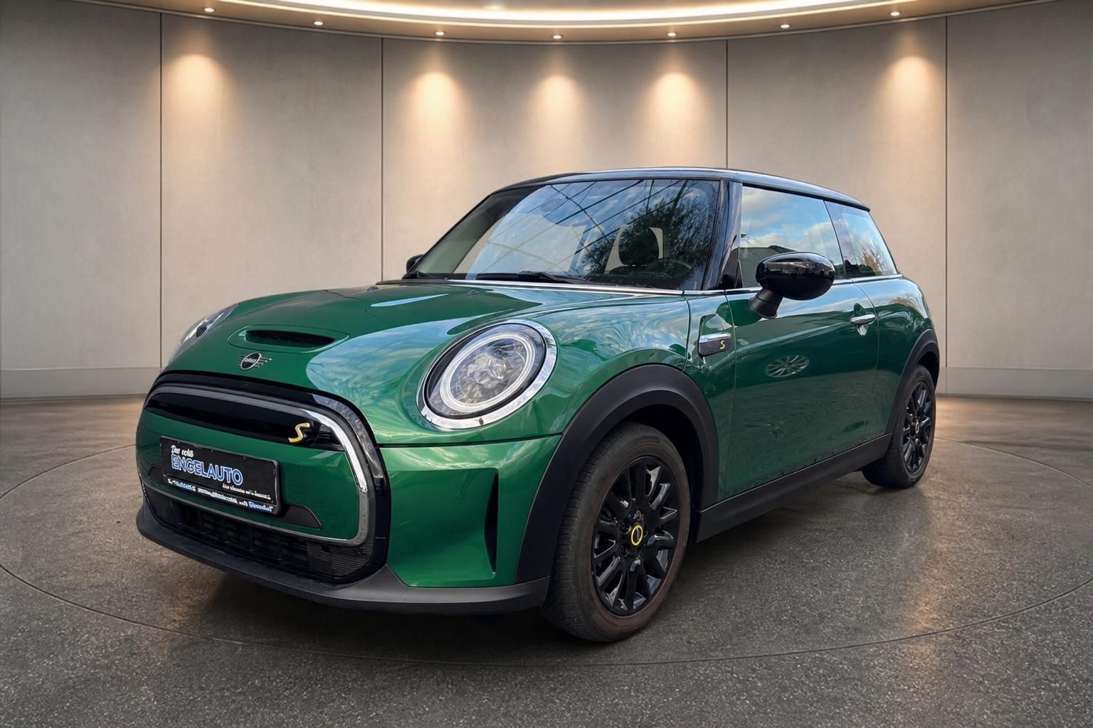 MINI Cooper SE Electric grün Dreiviertel-Frontansicht mit schwarzen Felgen im Showroom