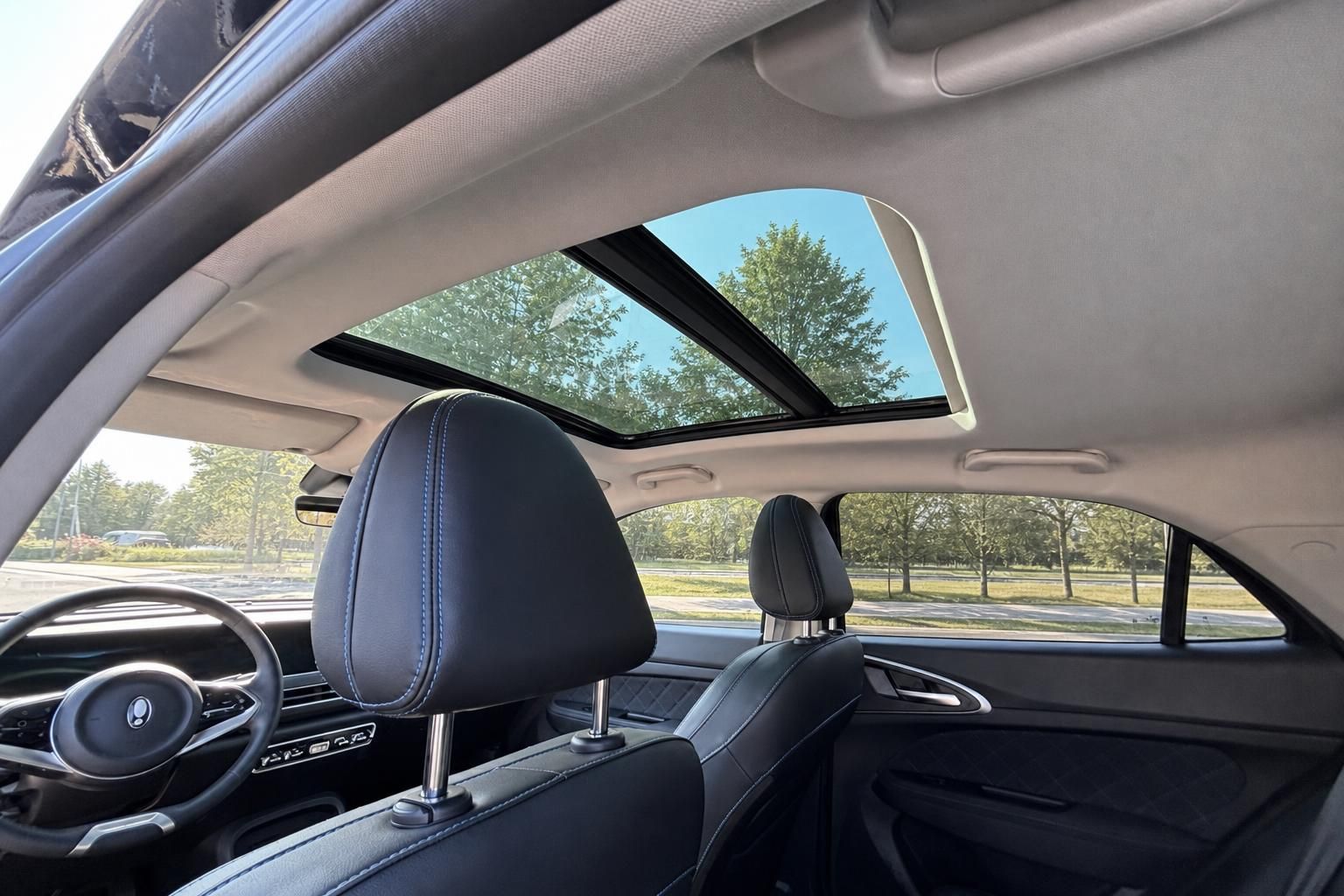 Fahrzeuginnenraum mit Panorama-Schiebedach, schwarzer Lederausstattung und Blick durch die Seitenfenster
