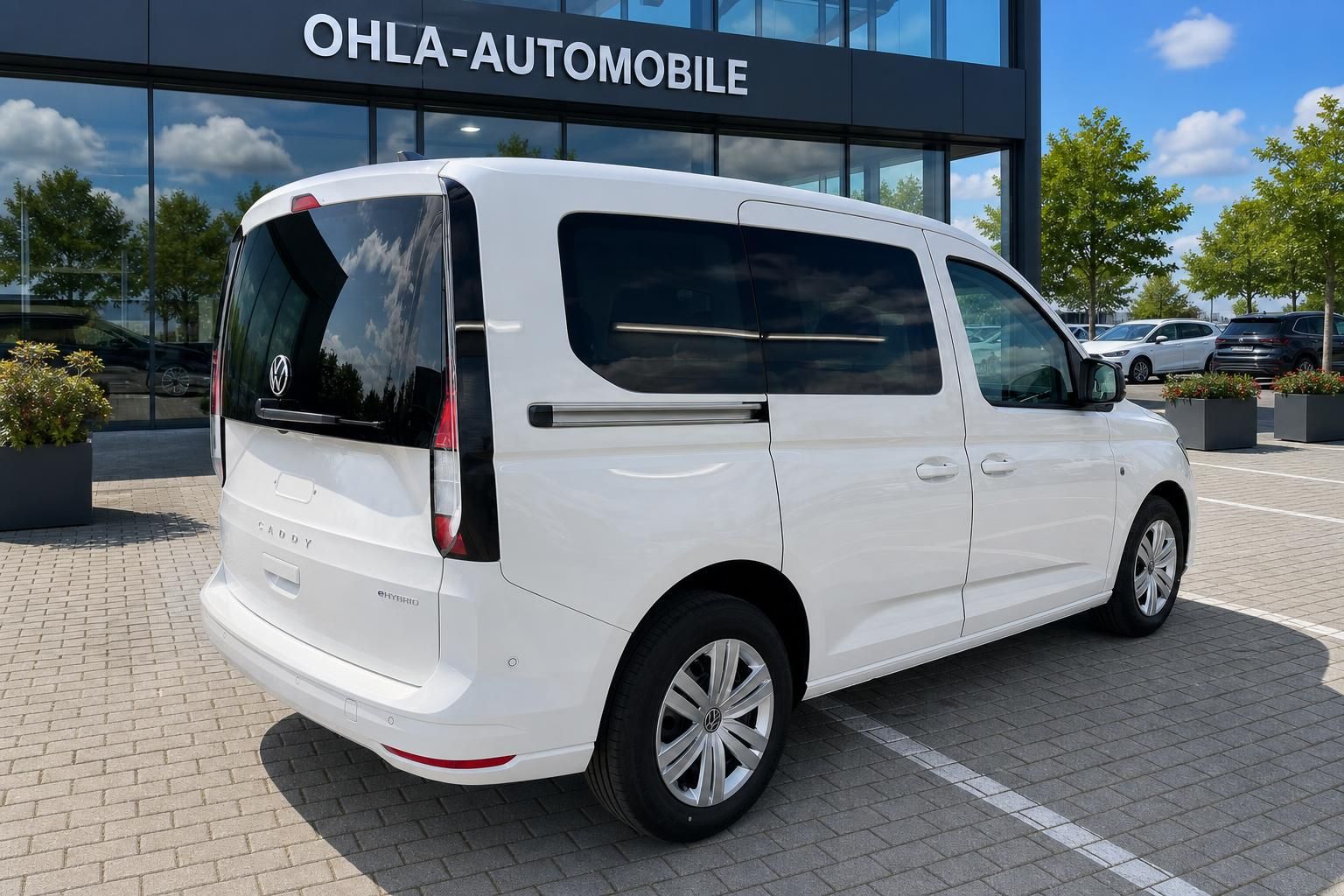 VW Caddy eHybrid weiß Heck- und Seitenansicht vor Autohaus Ohla-Automobile