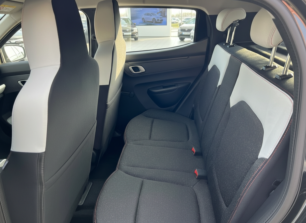 Rücksitzbank Innenraum mit schwarz-weißen Stoffsitzen und roten Ziernähten im Kleinwagen