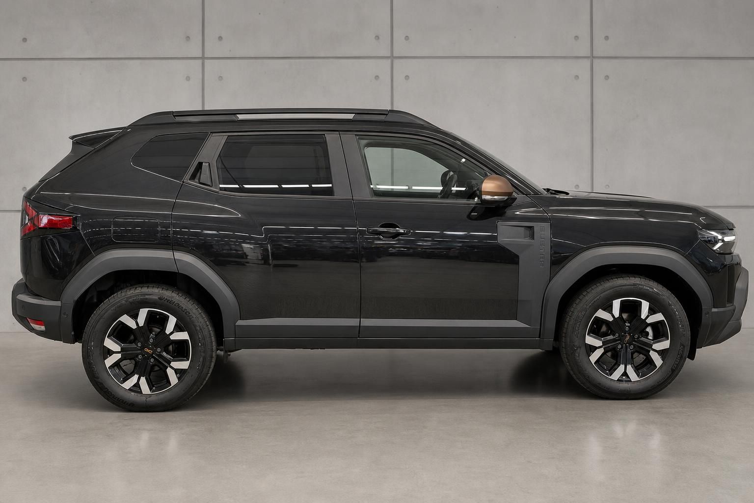 Dacia Duster schwarz Seitenansicht vor Betonwand
