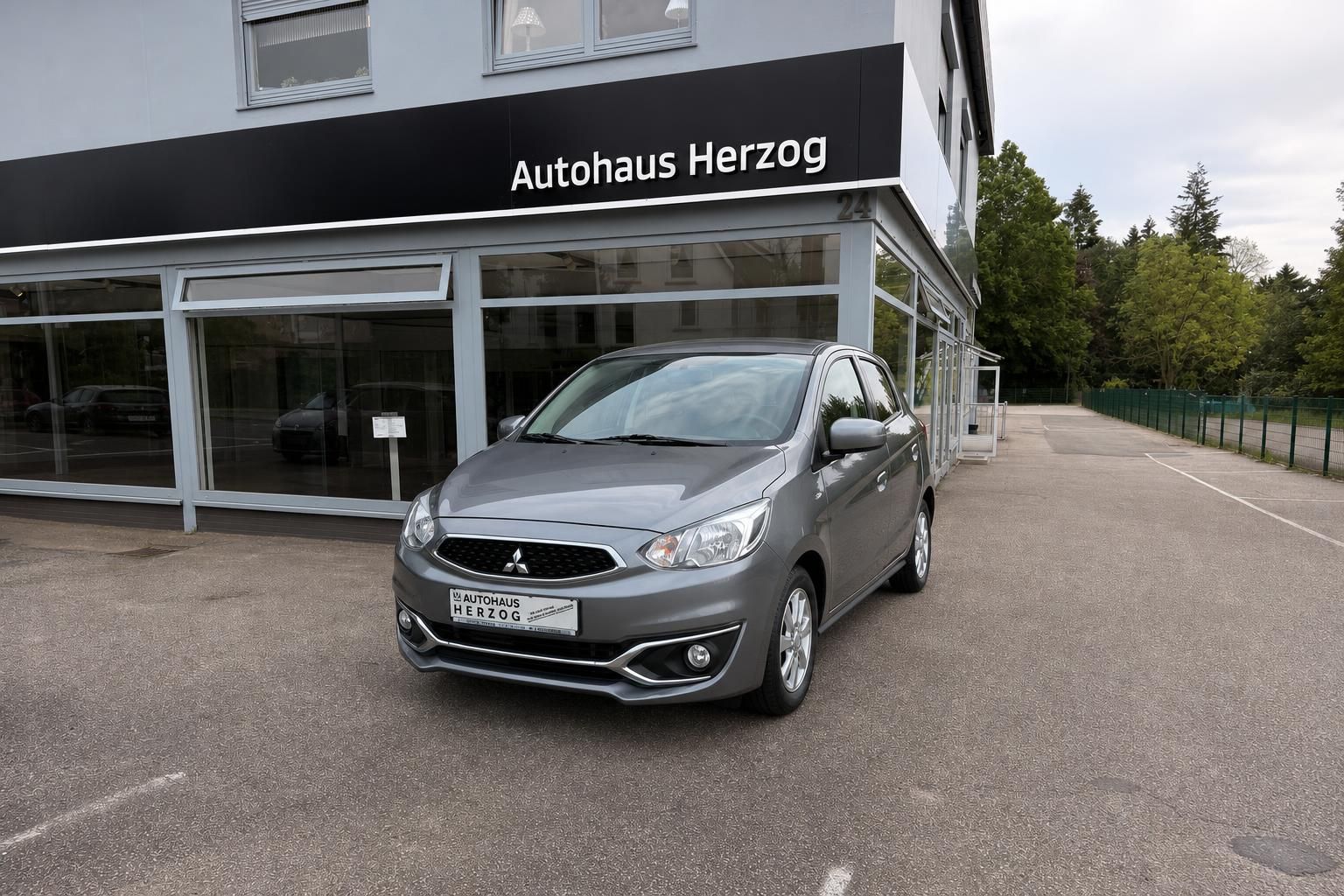 Grauer Mitsubishi Space Star Frontansicht vor Autohaus Herzog mit Händlerkennzeichen
