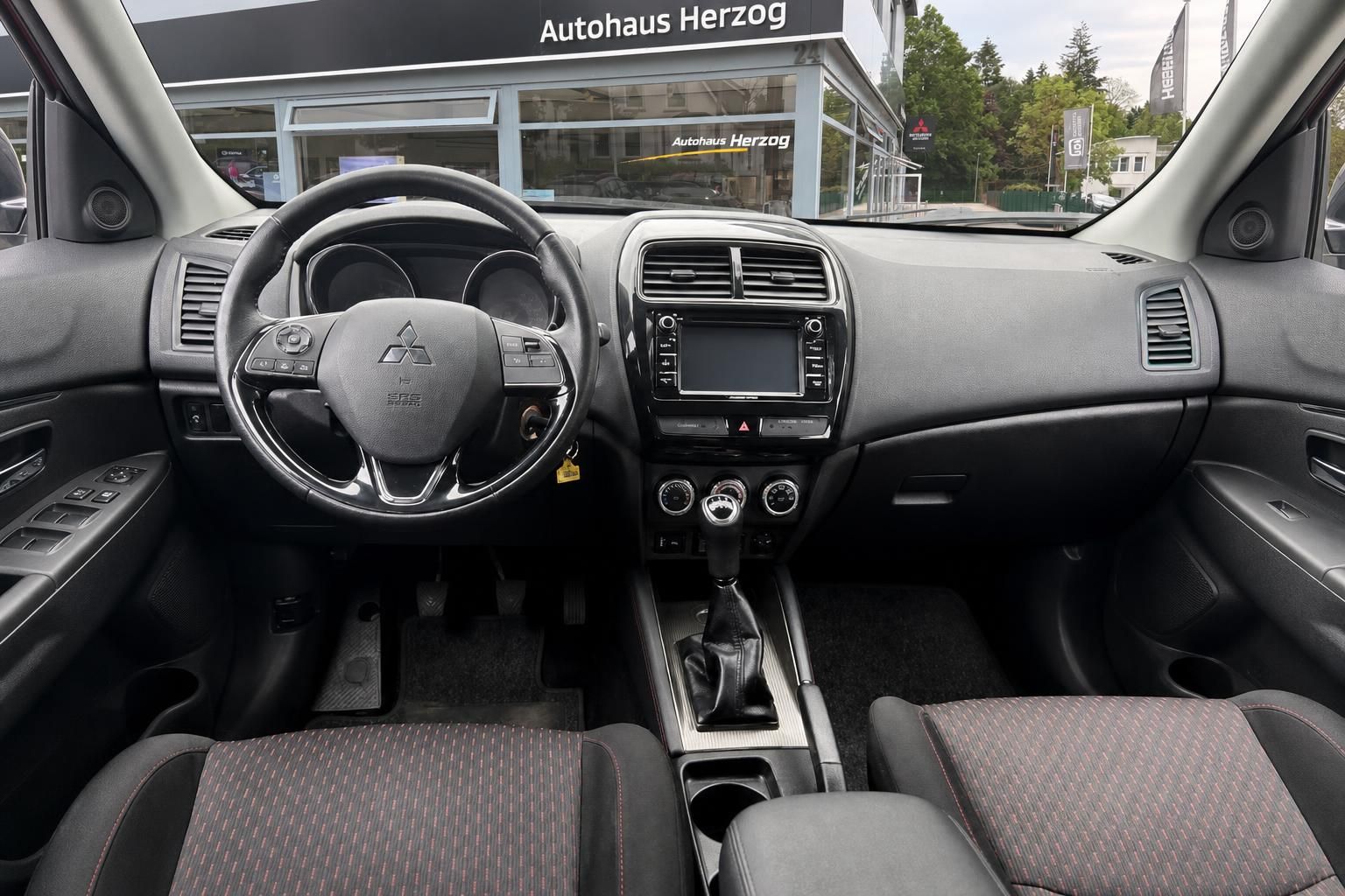 Mitsubishi Innenraum mit Lenkrad, Armaturenbrett und Sitzbezügen in Schwarz-Grau