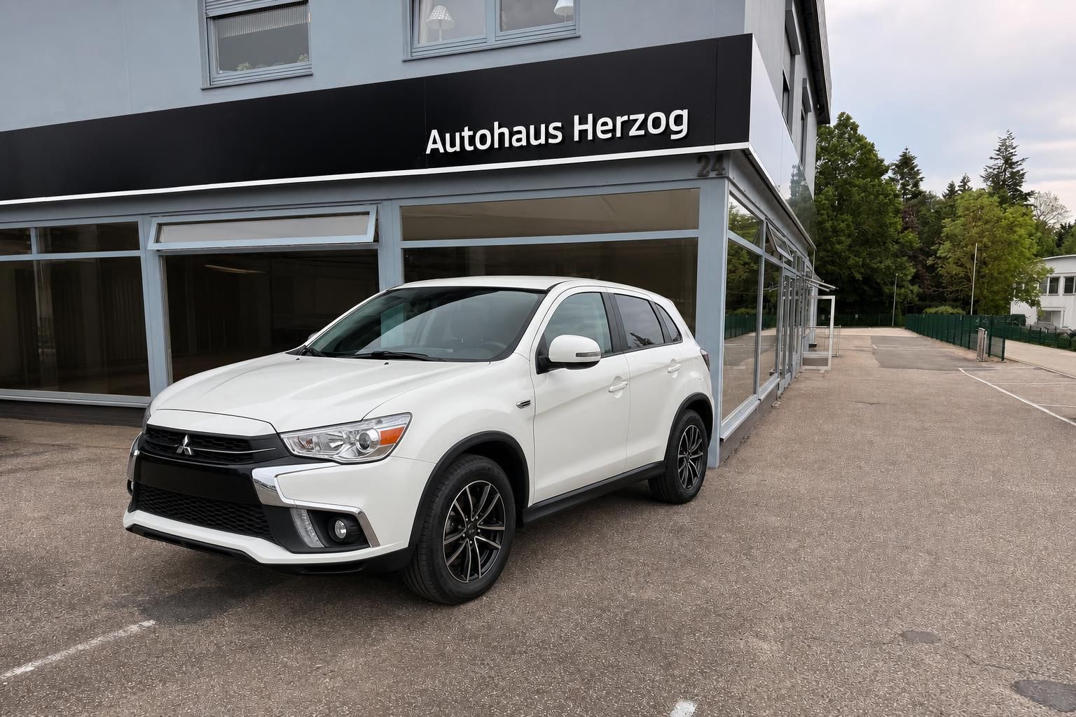 Weißer Mitsubishi ASX SUV vor Autohaus Herzog - Seitenansicht mit Leichtmetallfelgen