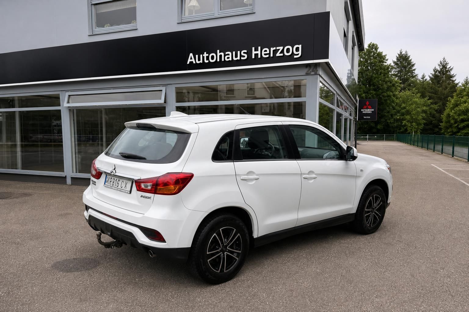 Weißer Mitsubishi ASX schräge Heckansicht links - kompakter SUV vor Autohaus mit Alufelgen