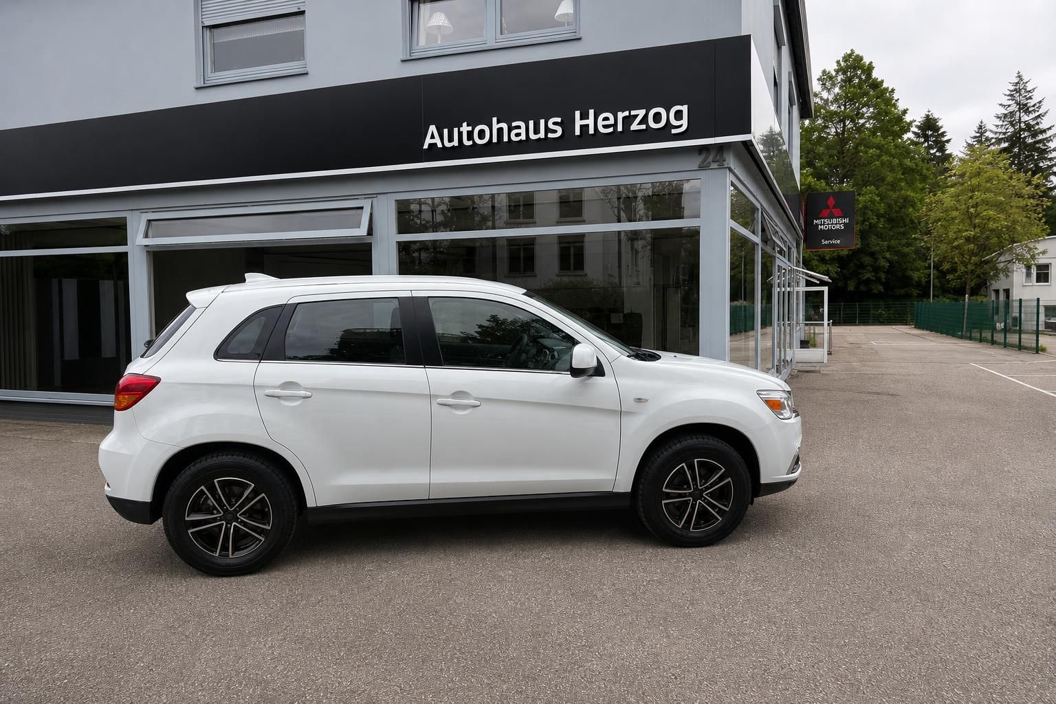 Weißer Mitsubishi SUV Seitenansicht - modernes Design mit schwarzen Felgen vor Autohaus