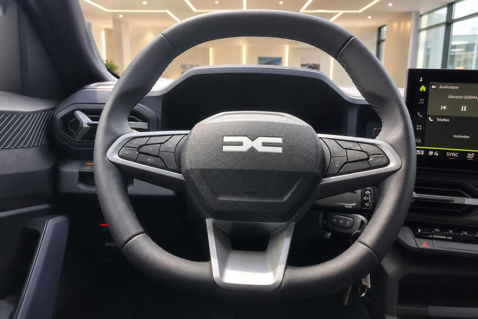 Lenkrad mit Multifunktionstasten und Dacia Logo im Fahrzeuginnenraum