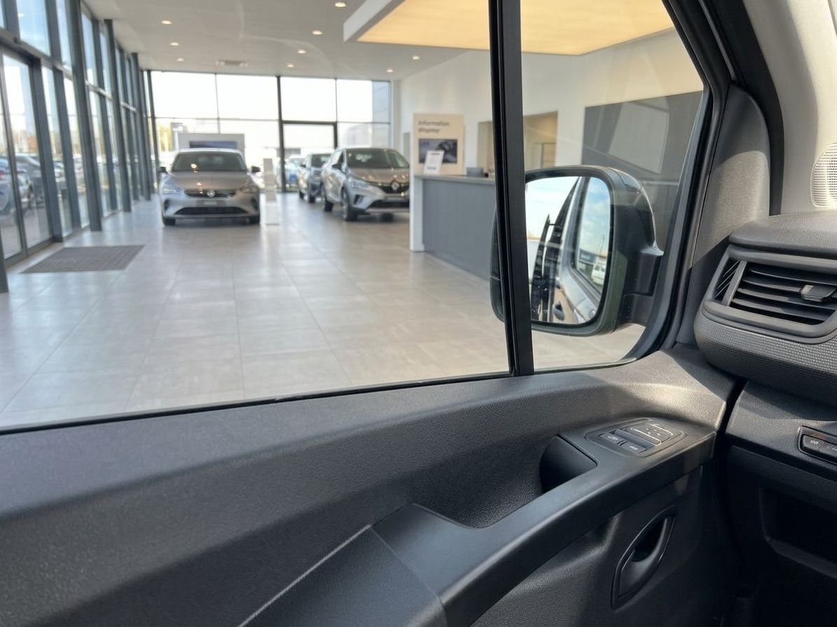 Blick aus dem Fahrerbereich durch geöffnete Fahrzeugtür auf Autohaus-Showroom mit Fahrzeugen