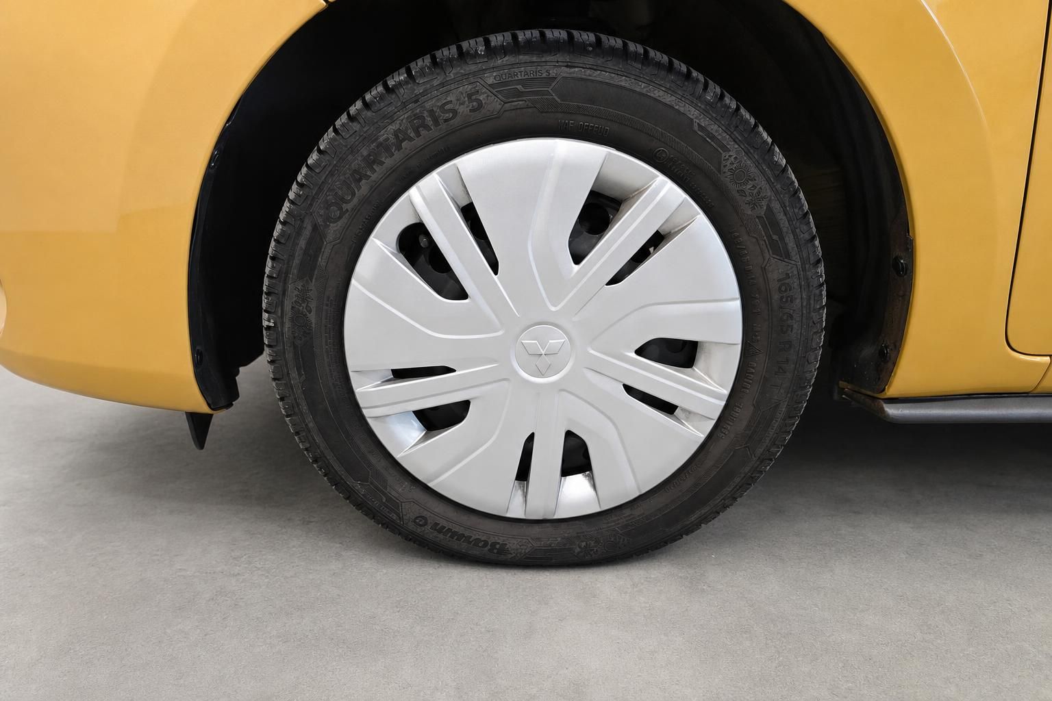 Vorderrad mit Radkappe am gelben Mitsubishi Kleinwagen