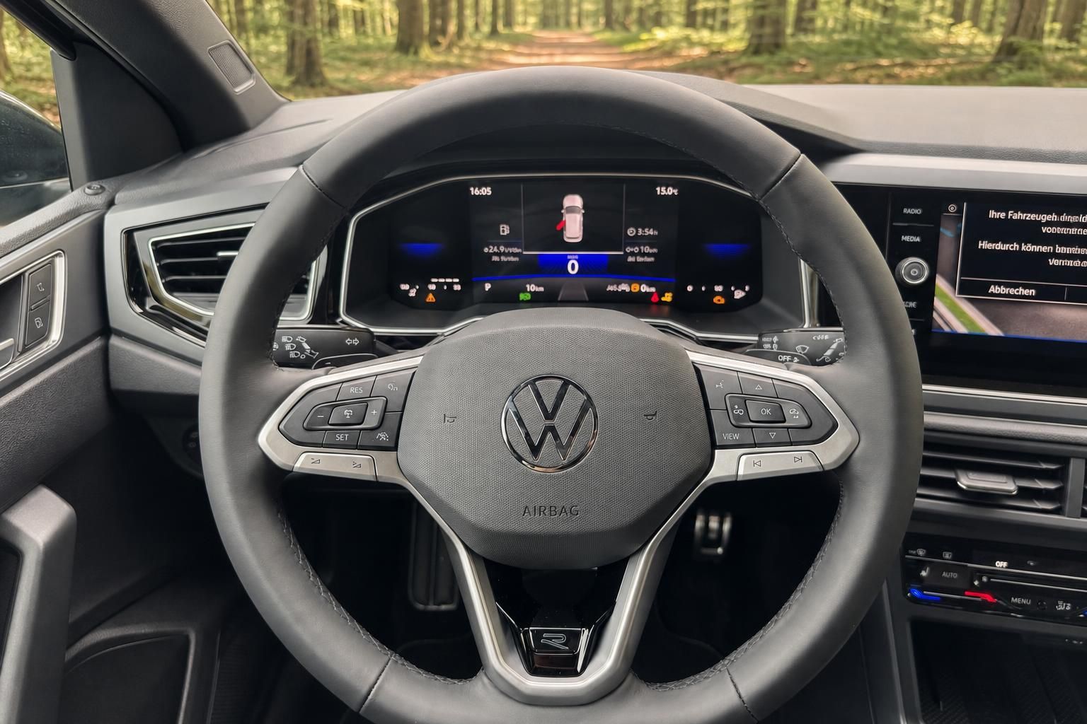 Volkswagen Lenkrad mit VW-Logo, digitales Cockpit und Multifunktionstasten im Fahrzeug-Innenraum