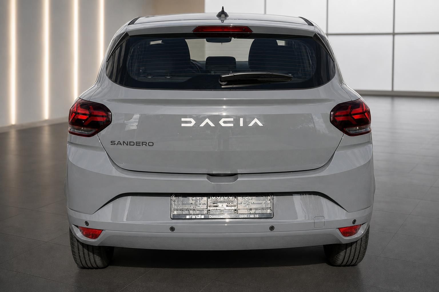 Dacia Sandero grau Heckansicht gerade im Showroom mit LED-Rückleuchten