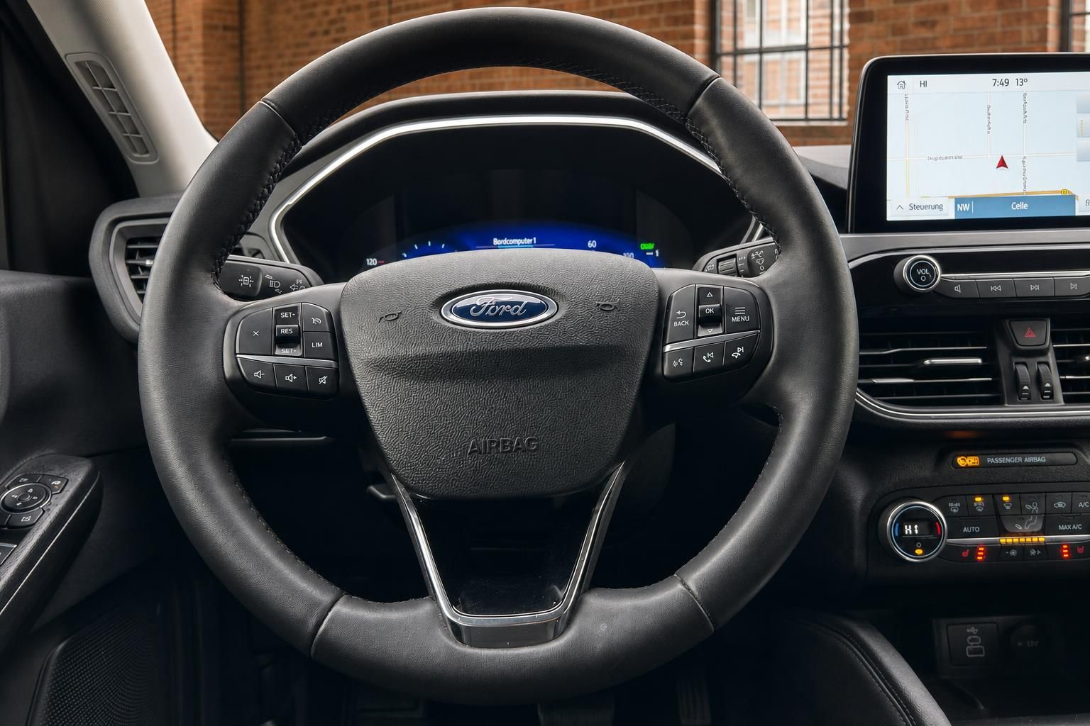 Ford Lenkrad mit Multifunktionstasten, Airbag und digitalem Tacho im Hintergrund