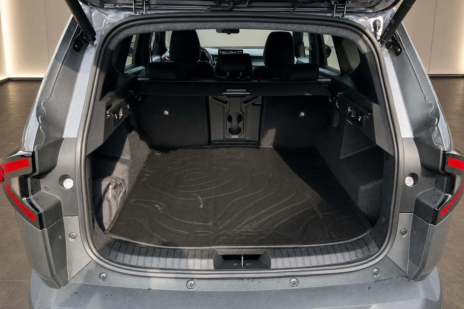 Kofferraum eines grauen SUV mit geöffneter Heckklappe und schwarzer Kofferraummatte