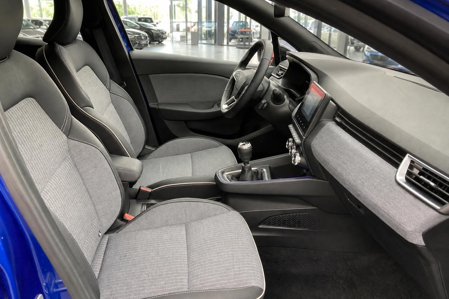 Fahrzeuginnenraum mit grauen Stoffsitzen und Schaltknauf im Renault