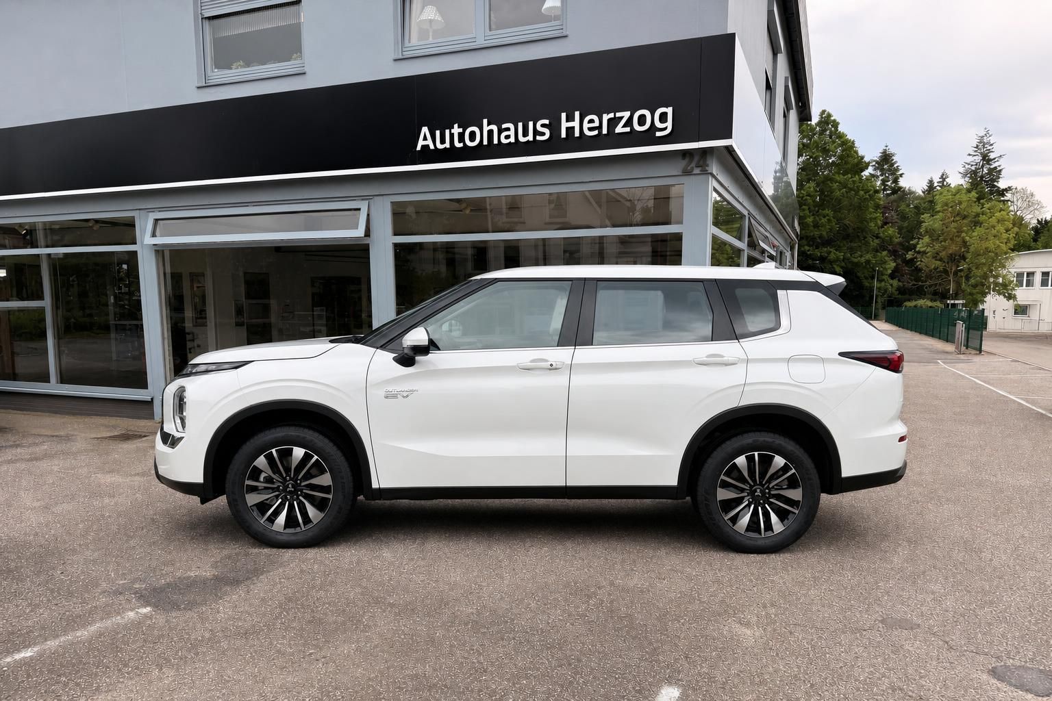 Mitsubishi Outlander EV weiß Seitenansicht vor Autohaus Herzog