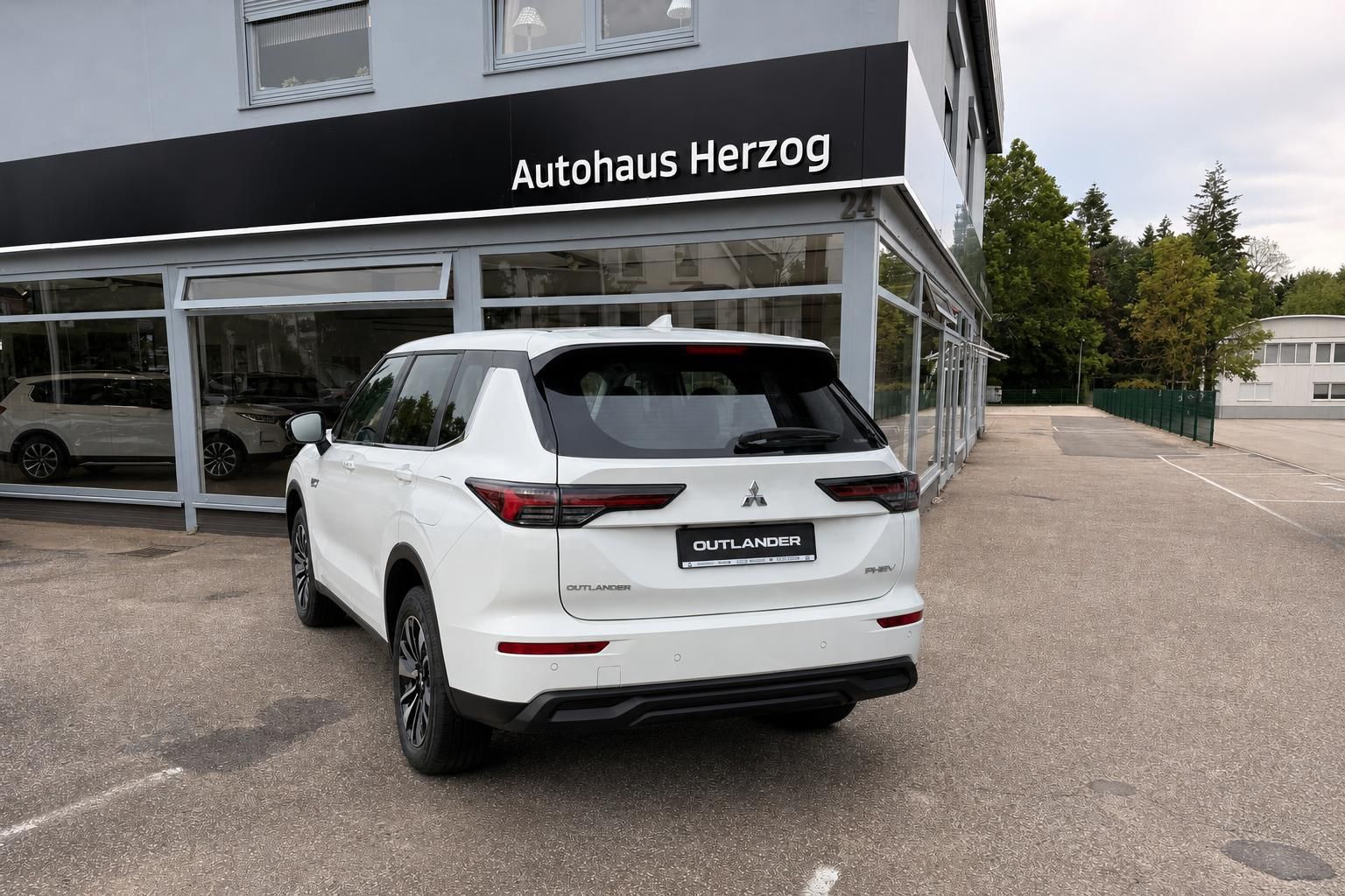 Mitsubishi Outlander PHEV weiß Heckansicht vor Autohaus Herzog