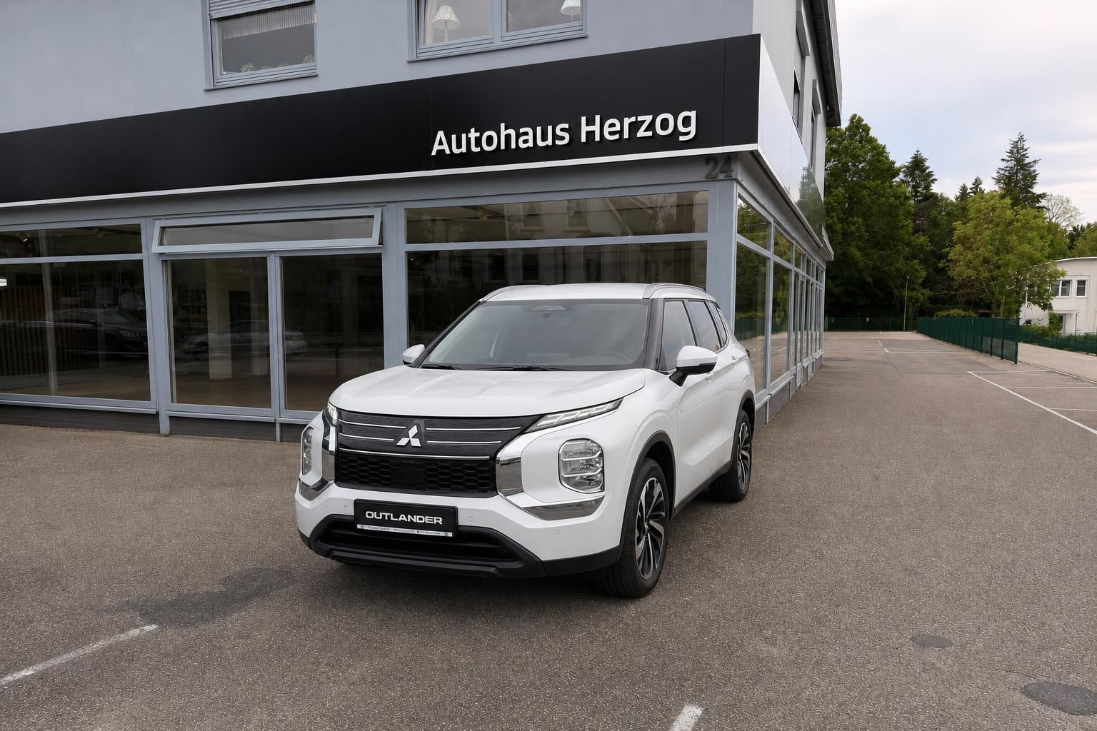 Mitsubishi Outlander weiß Frontansicht vor Autohaus Herzog