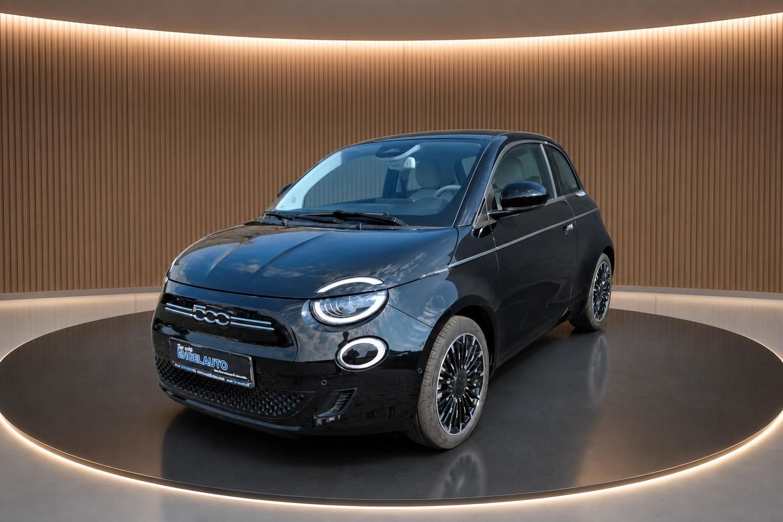 Fiat 500e schwarz Seitenansicht vorne auf Drehscheibe im Showroom