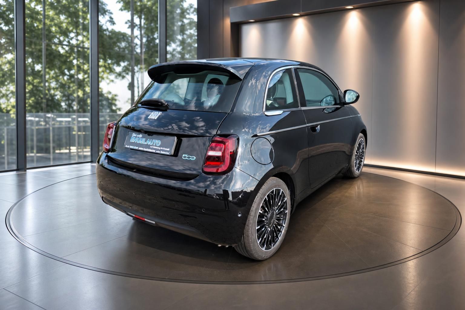 Fiat 500e schwarz Heckansicht im Autohaus mit Glasfront