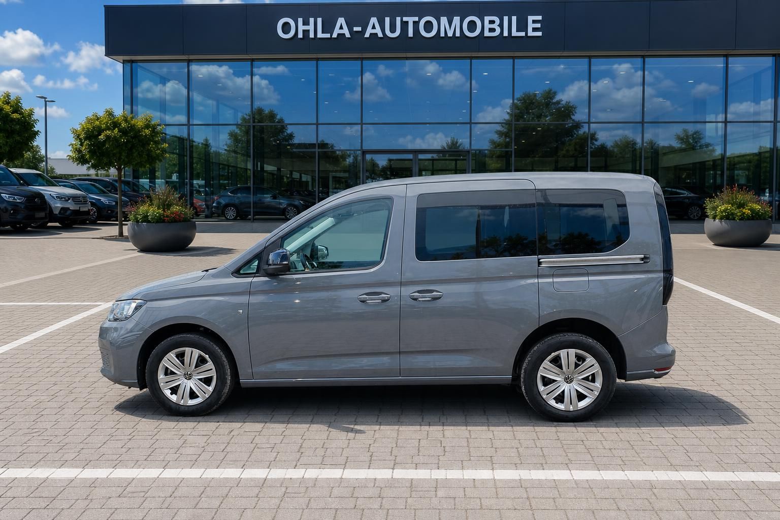 VW Caddy grau Seitenansicht vor Glasfassade Autohaus